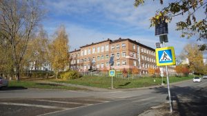 Brick building with trees in autumn near a road.